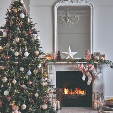 A living room with a lit marble fireplace and a decorated Christmas tree