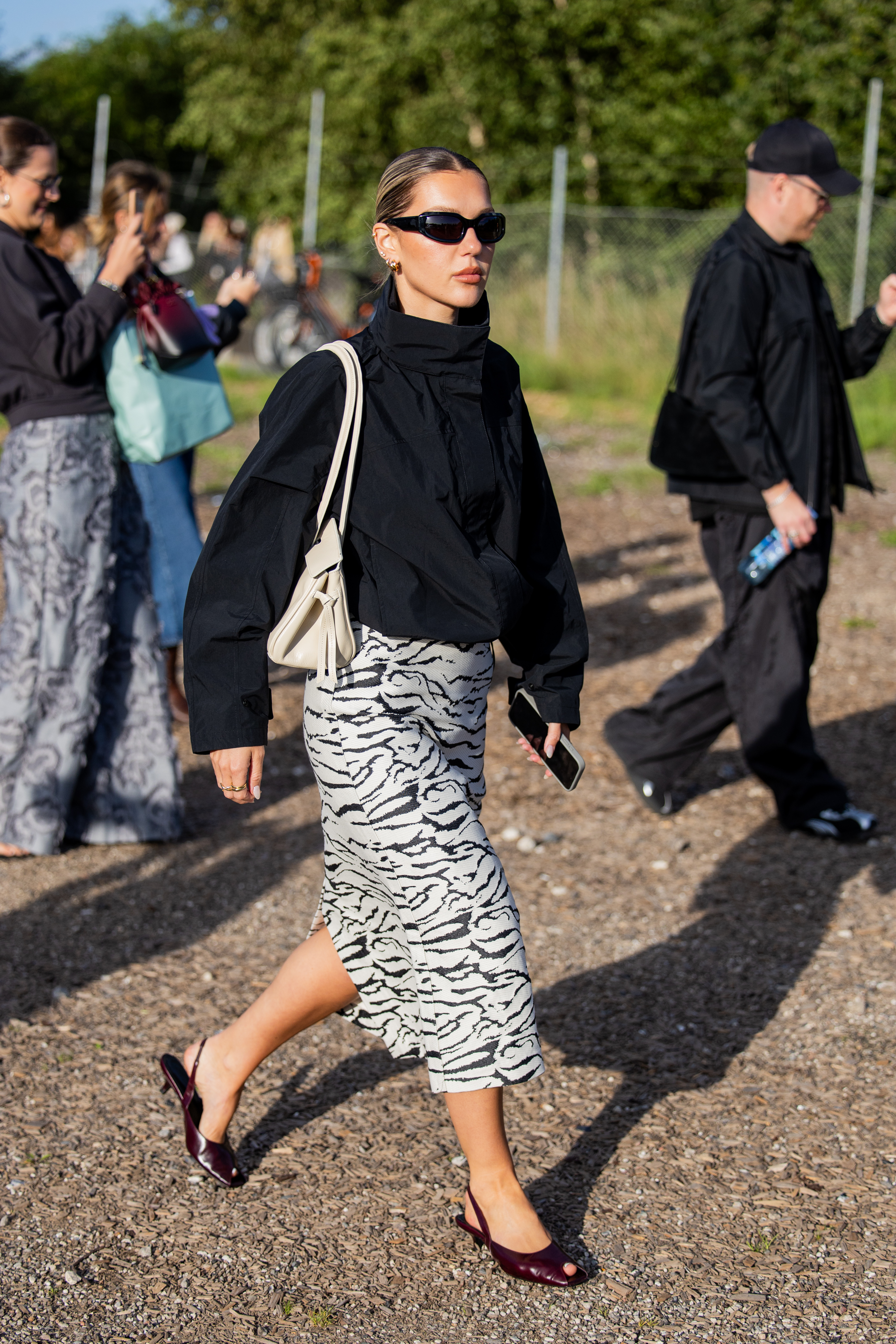 A guest wears black white skirt, black top, grey bag outside Rolf Ekroth during Copenhagen Fashion Week day two on August 05, 2025 in Copenhagen, Denmark.