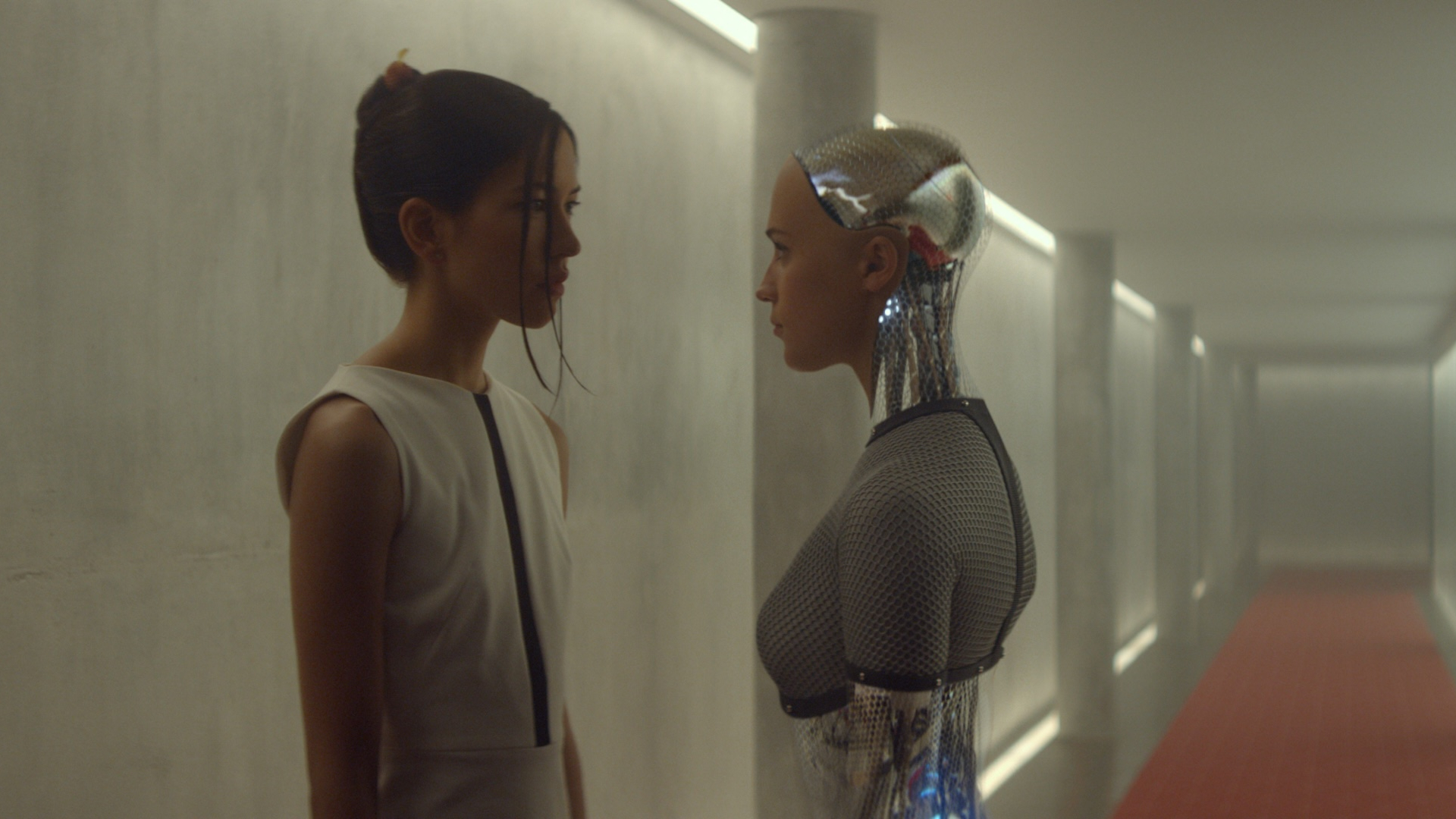 Two people standing in a long hallway staring at eachother