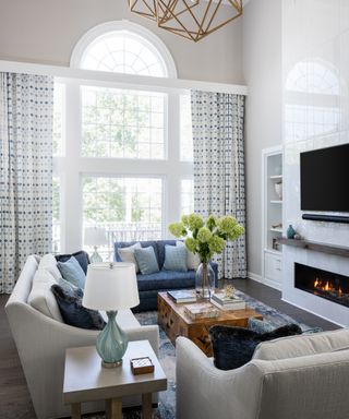 Living room with neutral couch and armchair and blue couch, coffee table and fireplace