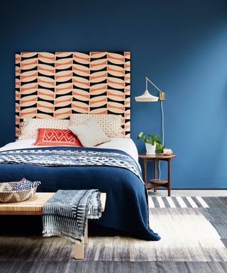 Bedroom ideas for teenagers in a blue bedroom with patterned headboard and orange accents.