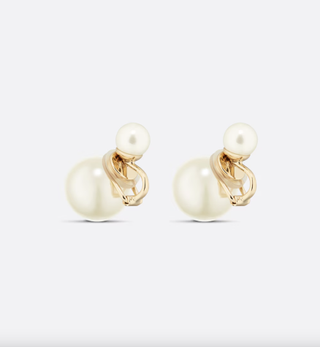 a pair of dior clip on earrings in front of a plain backdrop