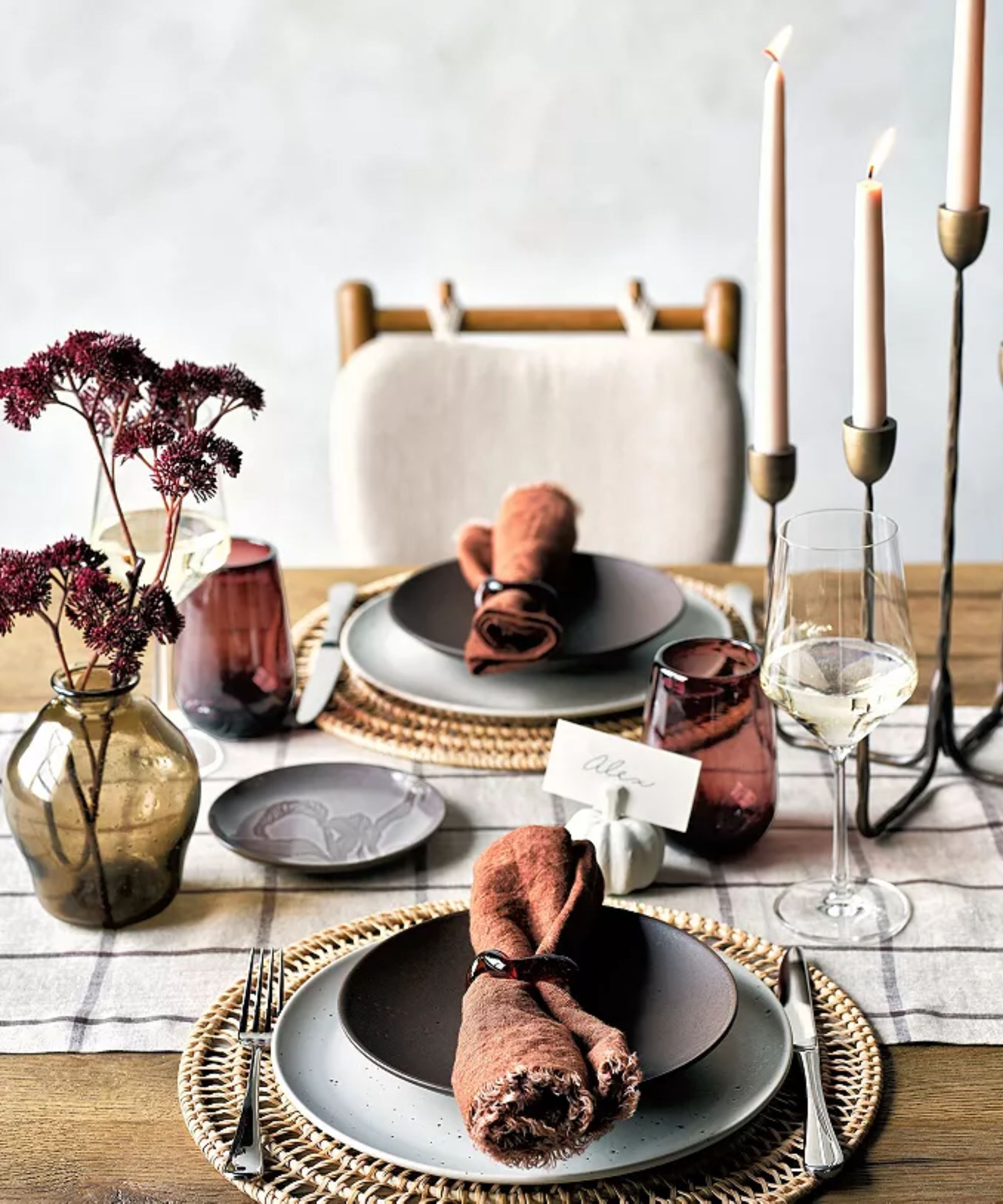Warm tablescape with burnt orange napkins, brown salad plates, white chargers and plum colored glasses