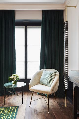 small arm chair and table in a hotel bedroom with green interior