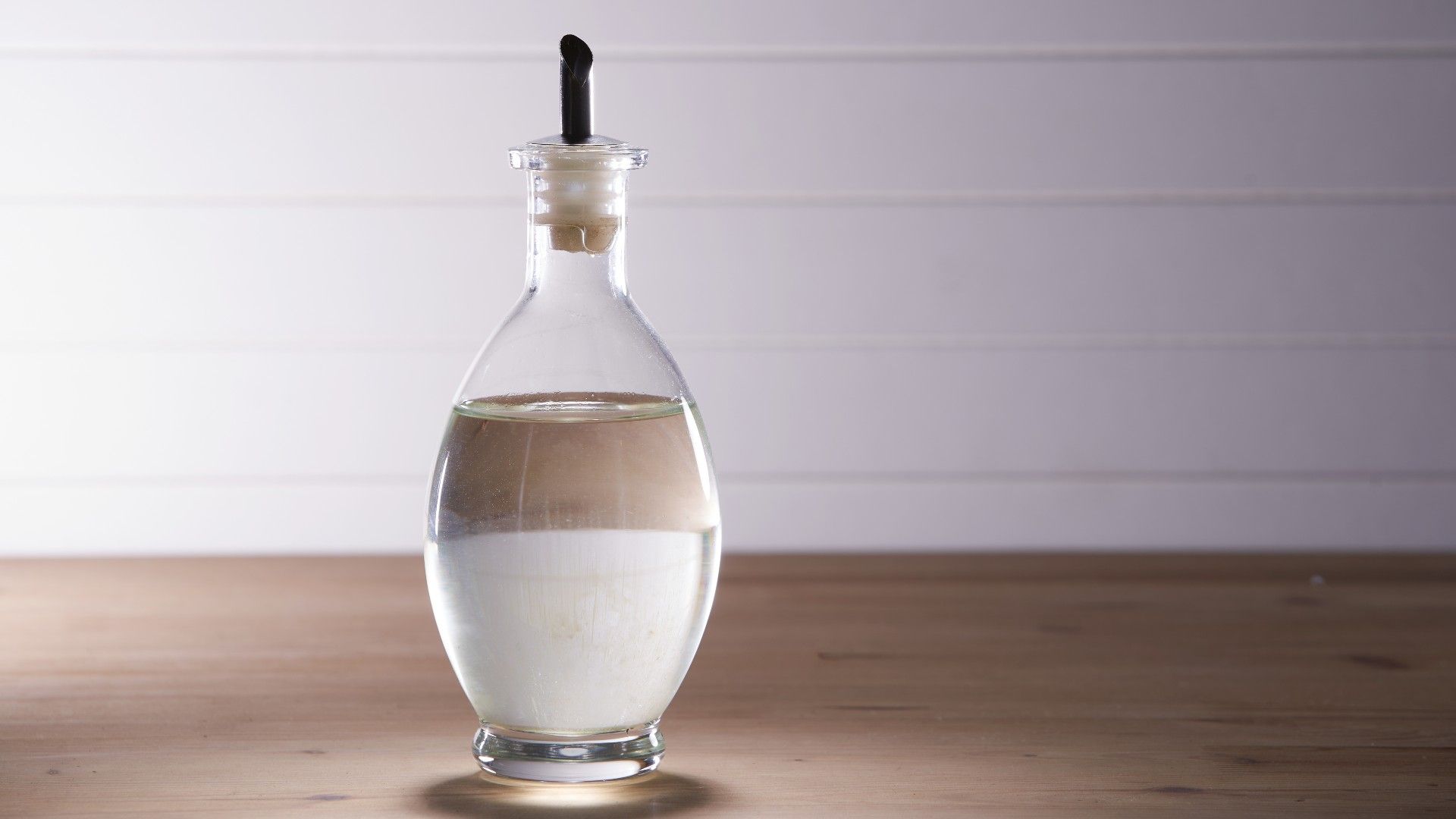 white vinegar in a dispenser glass bottle on a worktop