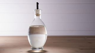 white vinegar in a dispenser glass bottle on a worktop