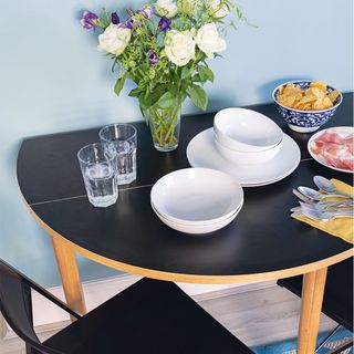blue wall with black drop leaf table and white china and glasses