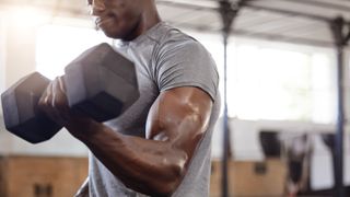 Person performing dumbbell workouts for triceps lifting a heavy dumbbell 