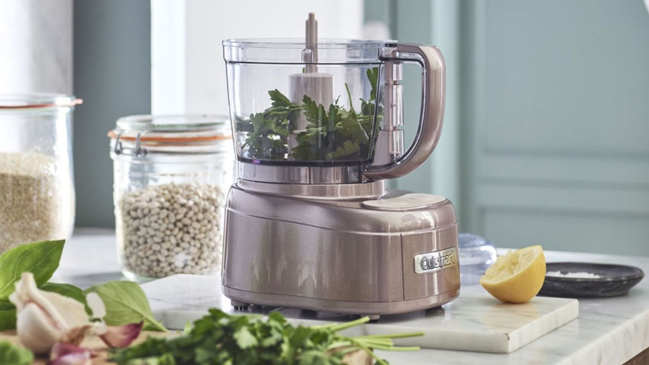 Cuisinart Mini Prep Plus Food Processor on the countertop with chopped herbs in front of it