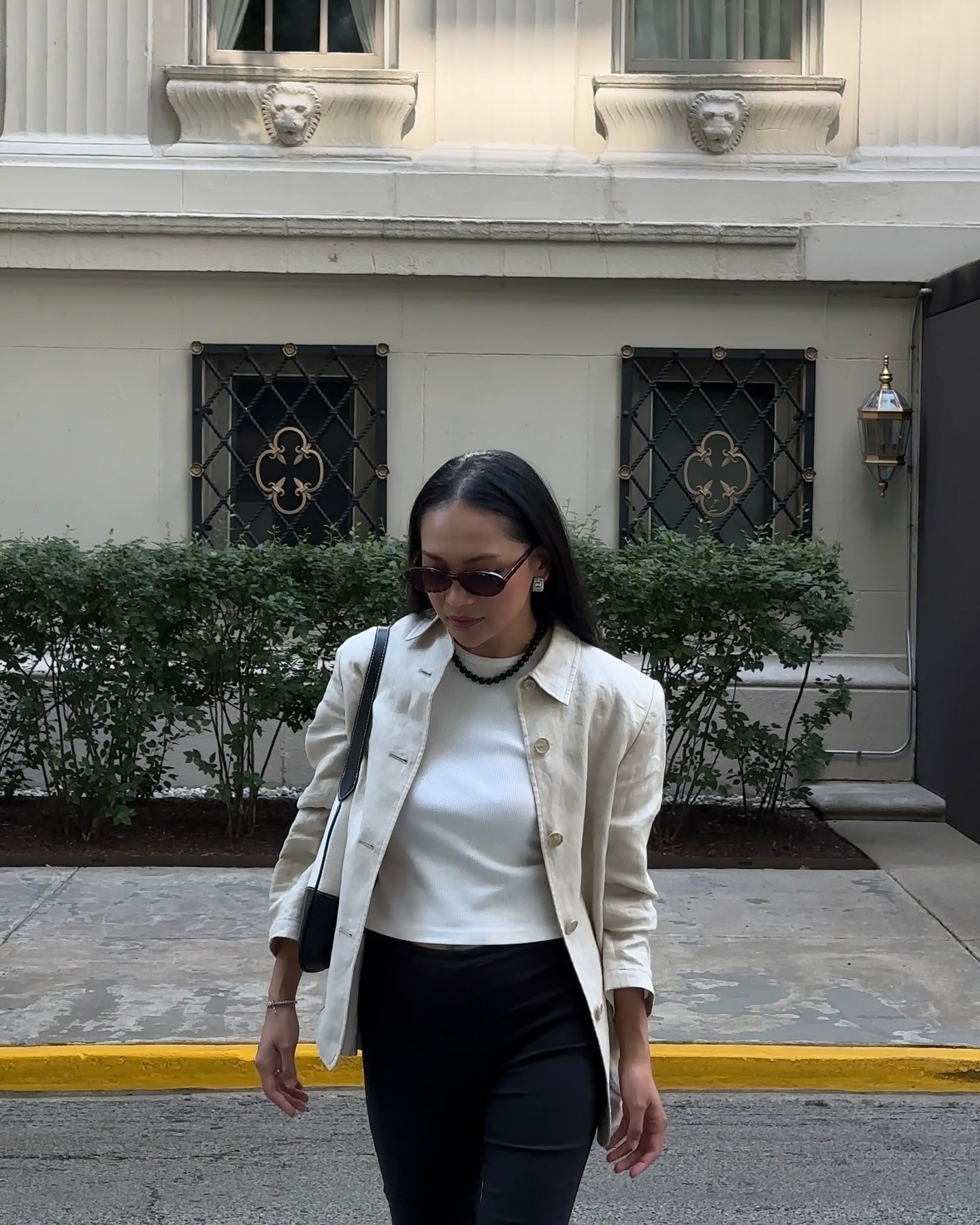 Mujer viste chaqueta de lino, camiseta blanca y pantalón negro.