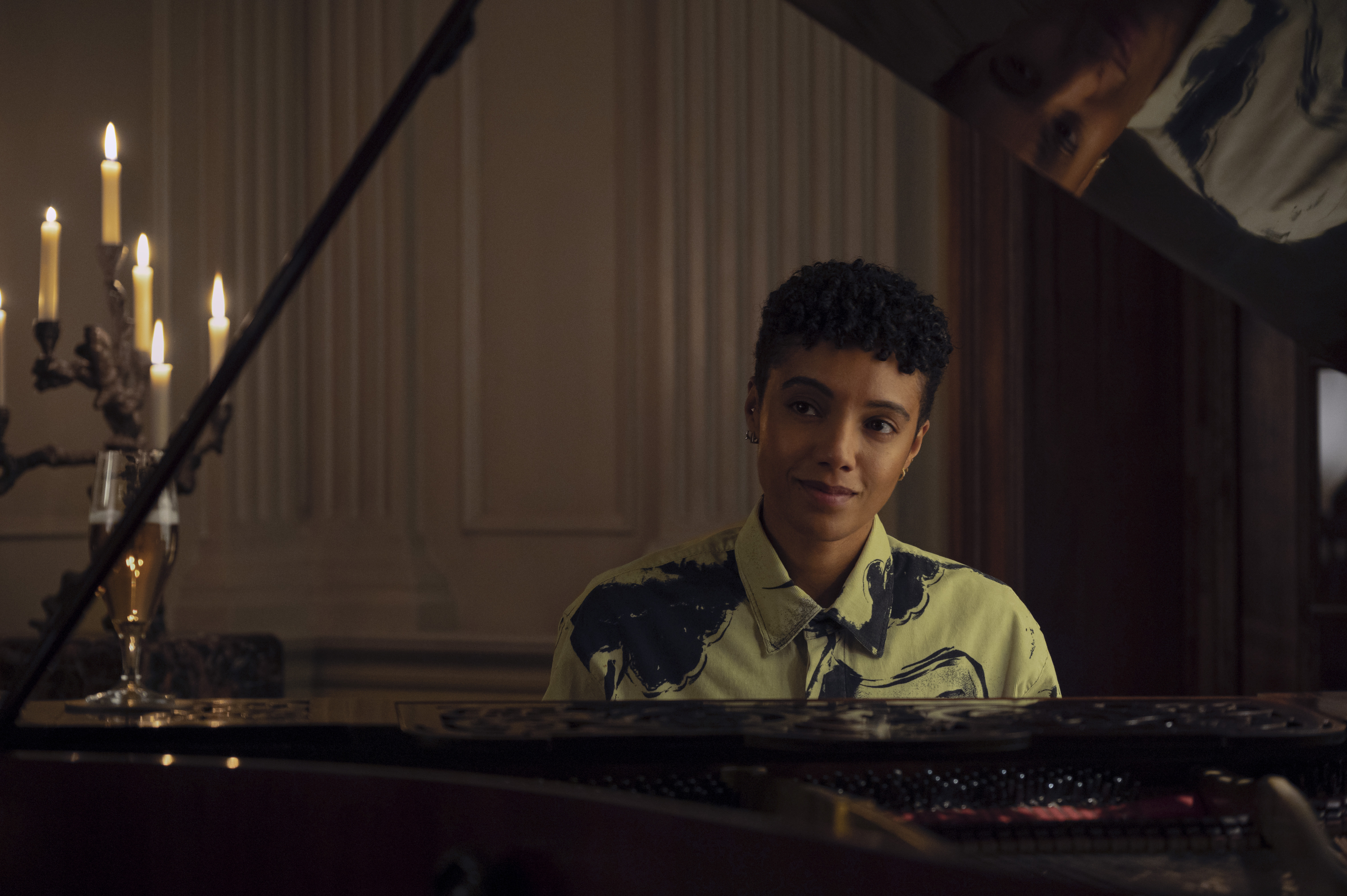 Maisie Richardson-Sellers as wolfie sitting at a piano in nine perfect strangers season 2