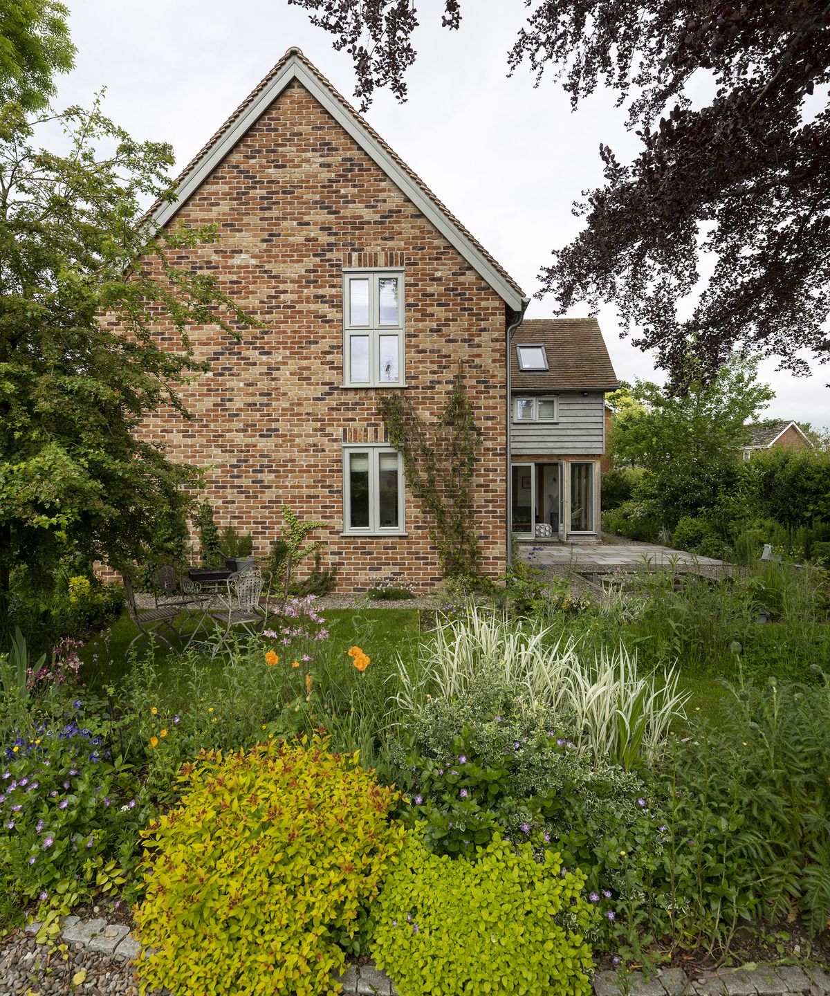 Exterior of a two storey oak frame house with brick and wood cladding and garden plants