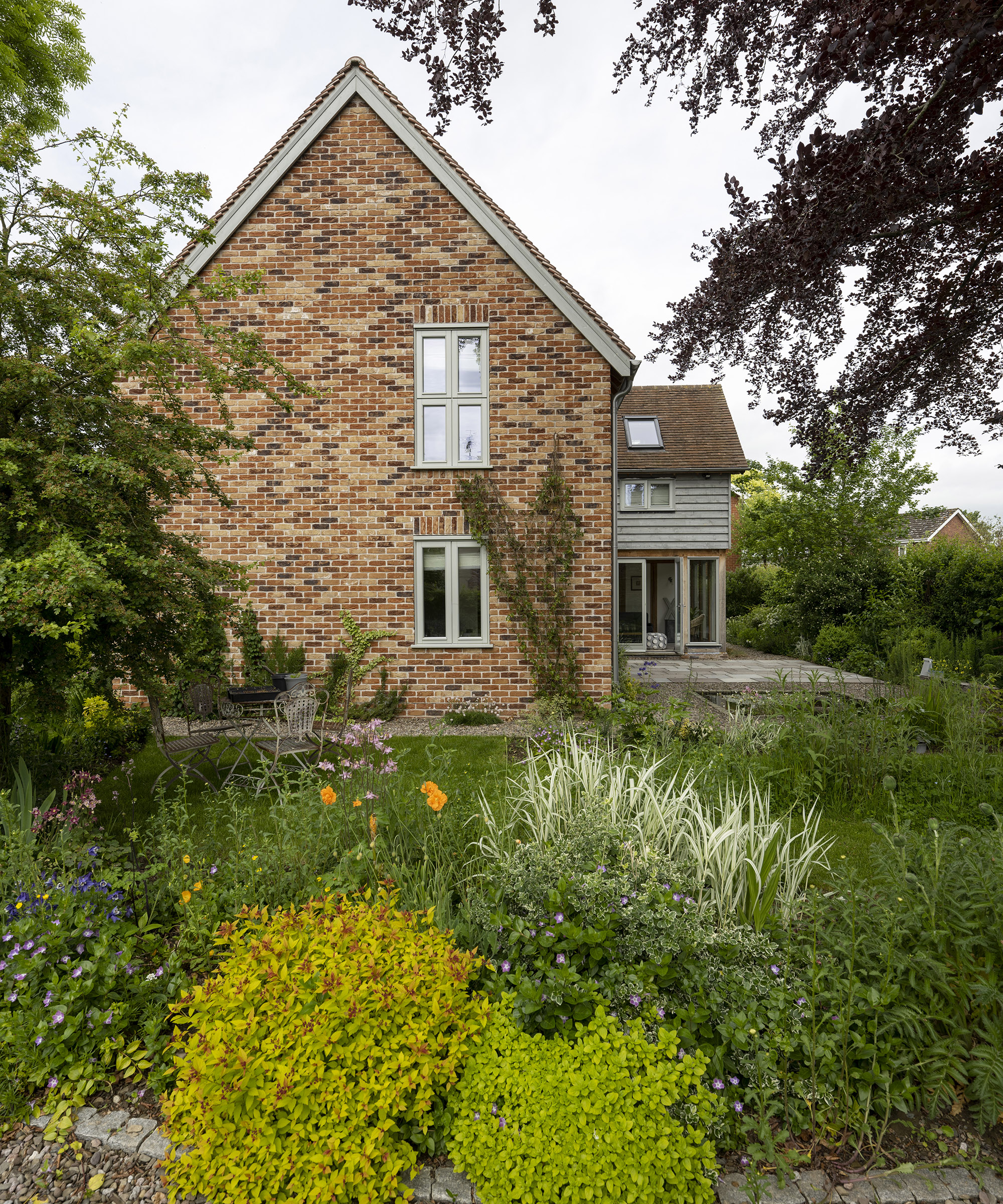 Exterior of a two storey oak frame house with brick and wood cladding and garden plants
