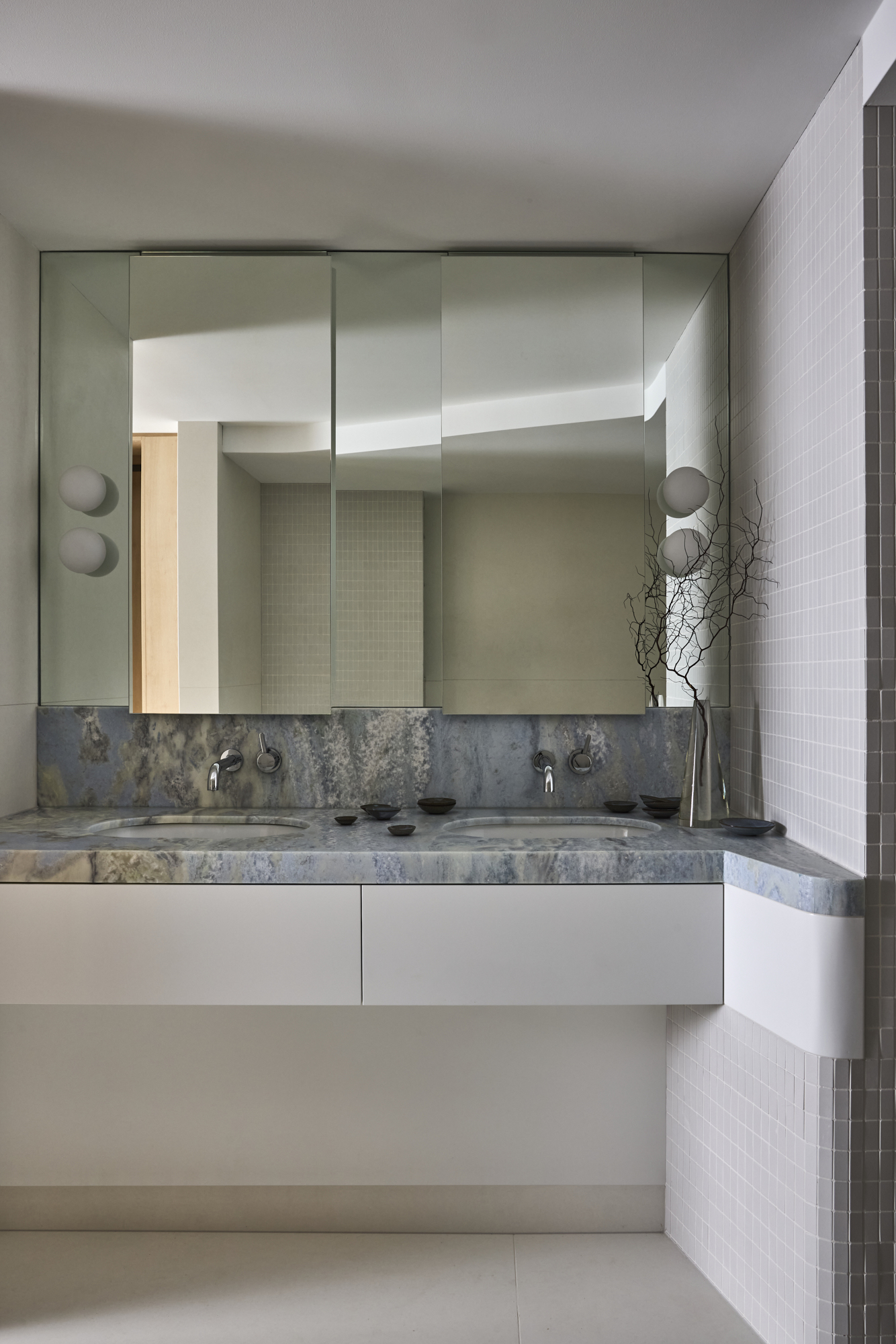 a bathroom with a cool white color, and a light blue countertop and mirrored wall