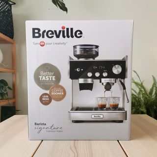 The Breville Barista Signature Espresso Machine in its packaging on a wooden table