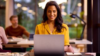 A young woman is working on a laptop in a relaxed office space