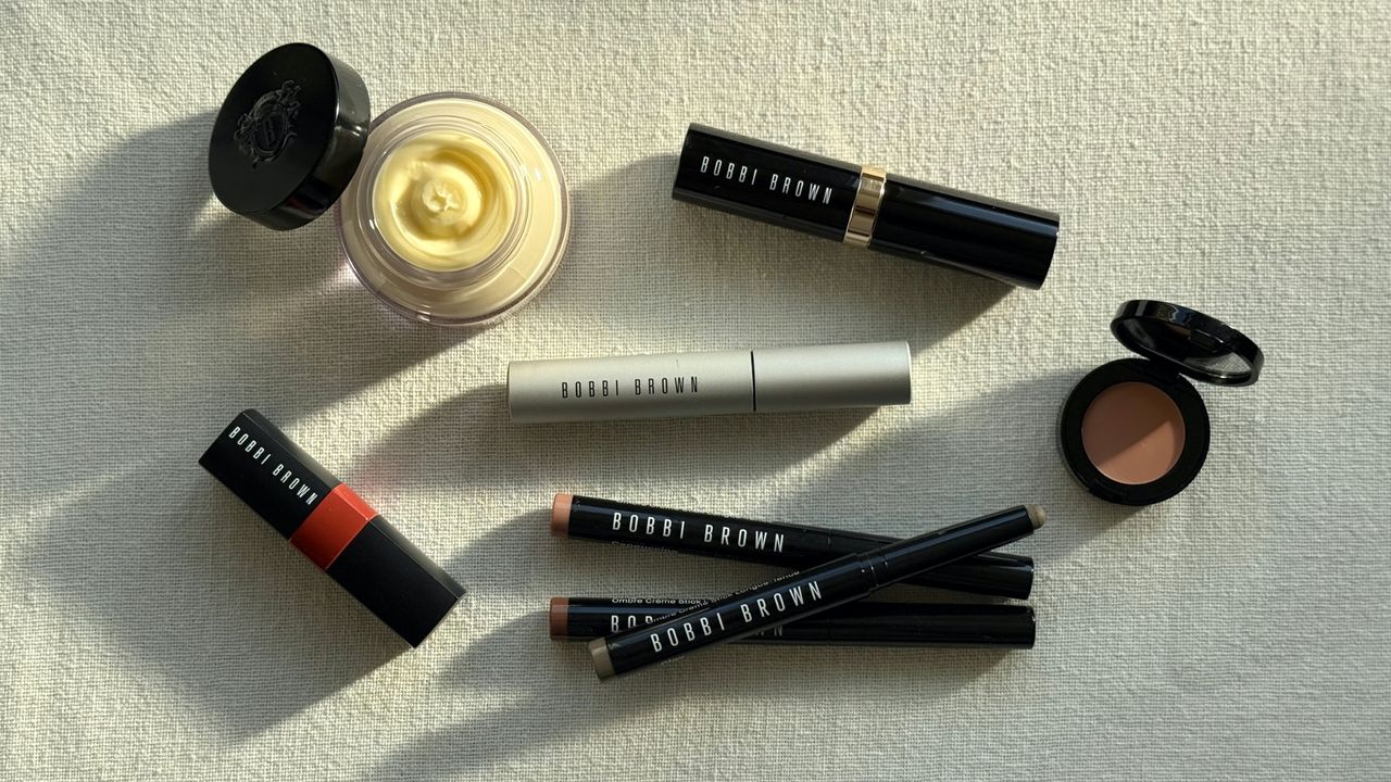 A bird&#039;s eye view of a flatlay of a selection of the best Bobbi Brown products featured in this guide, laying on a cream linen background