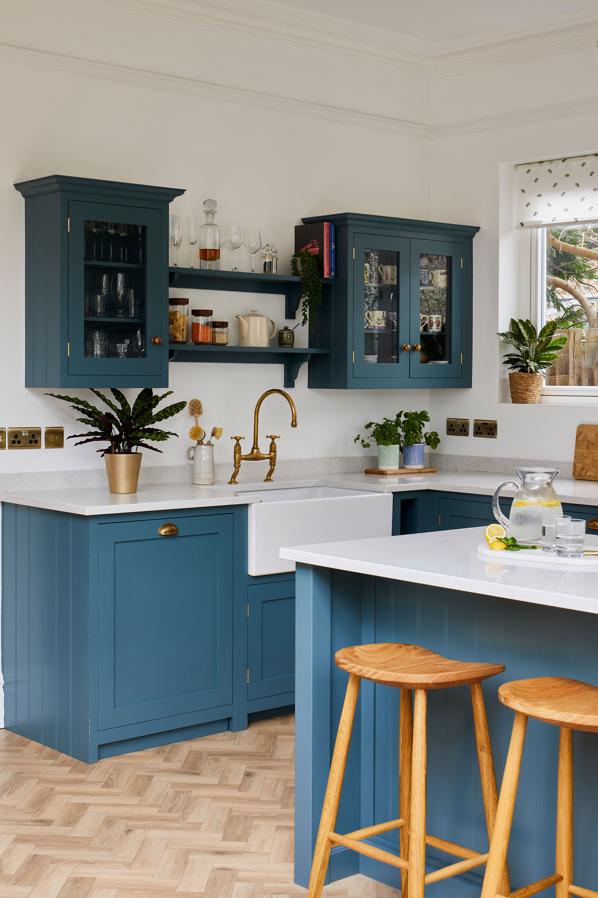 A conservatory-style blue kitchen extension in an Edwardian home with blue cabinetry, island and wooden bar stools