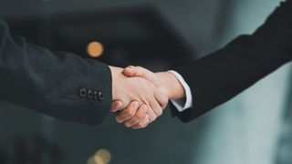 Close up of a handshake with between people in suits.