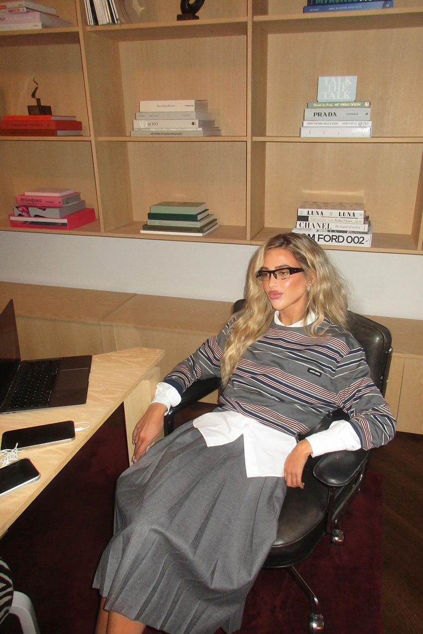 A woman wearing a striped shirt and a gray skirt.