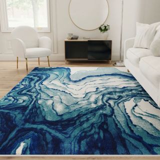  Ivy Bronx Omari Power Loom Ocean Blue Rug in living room with white sofa