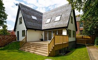 An unusual SIPs home in a Manchester suburb featuring a steep-pitched roof, basement and large decked area.