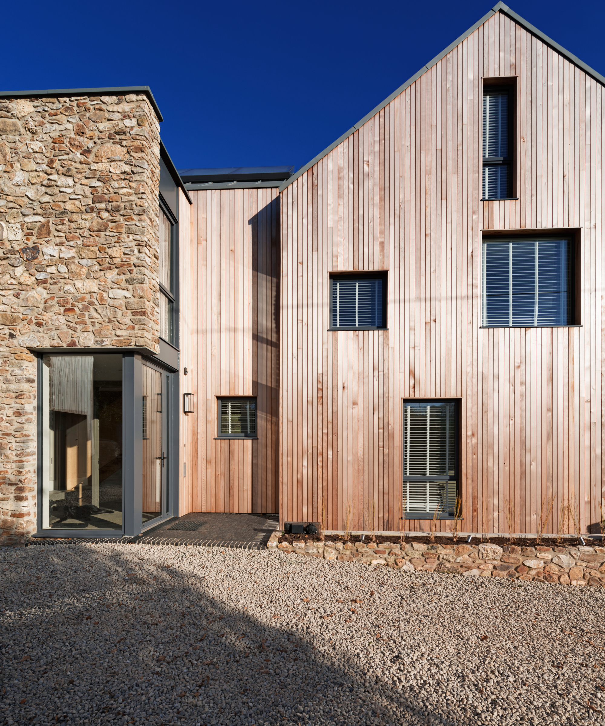 contemporary house featuring cedar cladding next to a section finished in stone