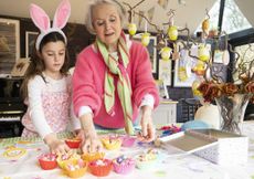 Grandmother and granddaughter making Easter cakes together in kitchen