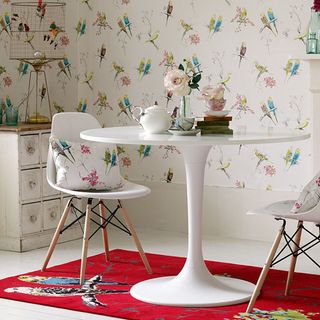 room with brid wallpaper wall and white round table and chair and rug