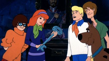 Velma, Daphne, Fred, Shaggy, and Scooby-Doo looking at a giant key which is also a clue