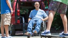 Man with spinal cord injury in wheelchair watching his son on skateboard 