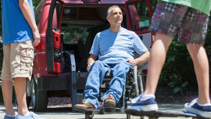 Man with spinal cord injury in wheelchair watching his son on skateboard