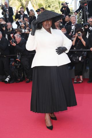 Yseult attends the 2024 Cannes Film Festival red carpet wearing a white blazer with a black A-line skirt