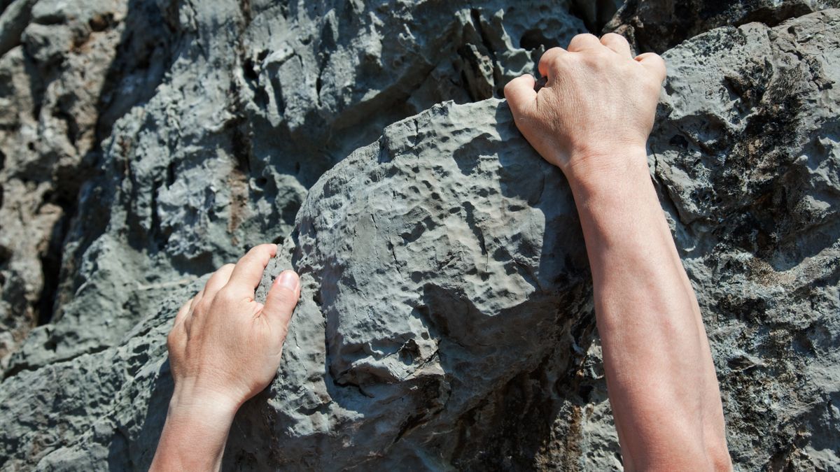 Man&#039;s hands climbing rock face