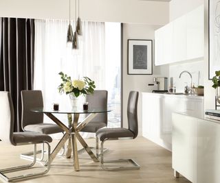 kitchen dining area with chrome lighting, chrome legged glass table and chairs, white kitchen units