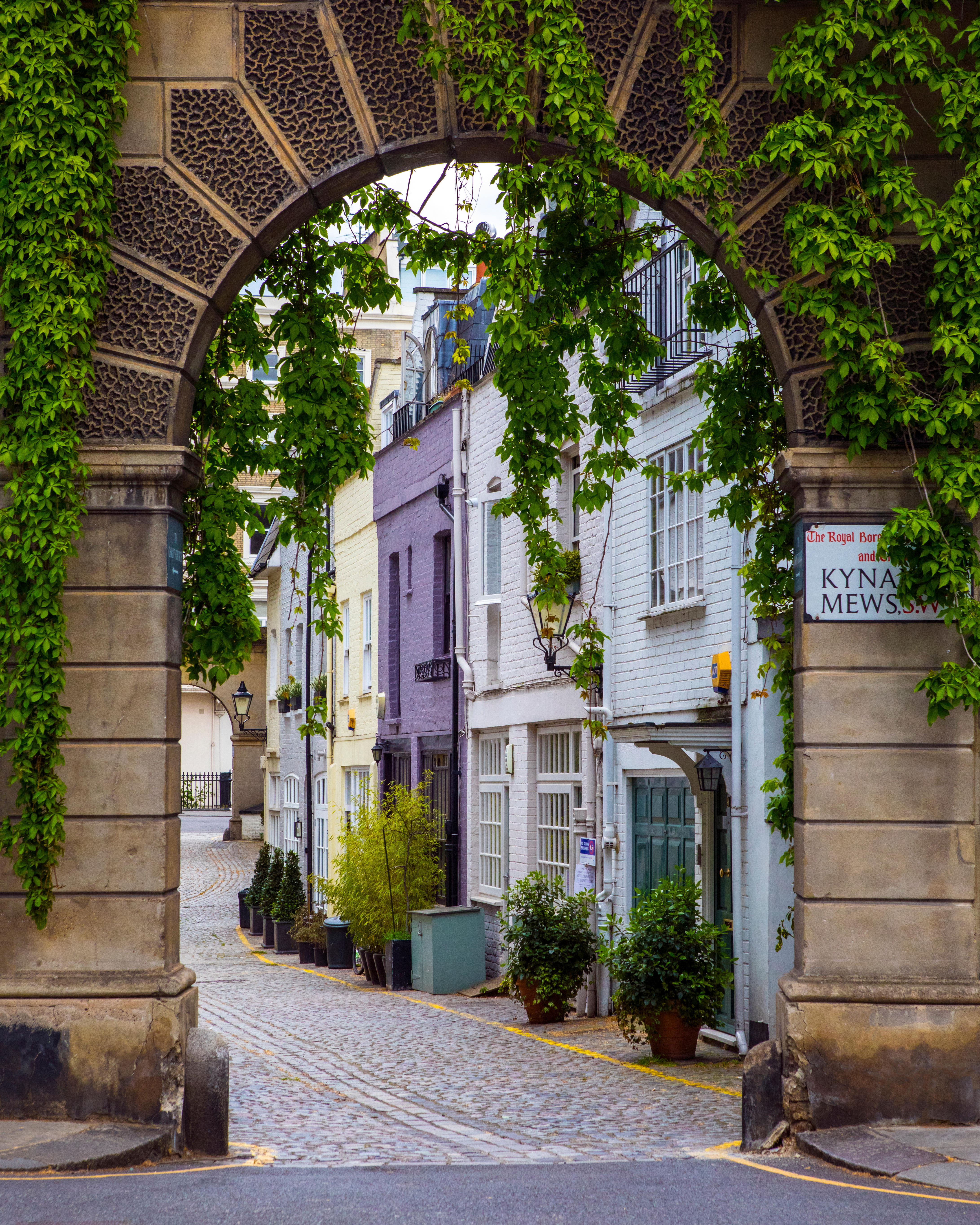 A view of the beautiful Kynance Mews in Kensington through a stone archway