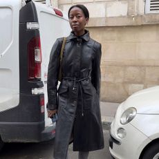 Influencer @sylviemus_ wears grey tights with peep-toe shoes and a black leather trench coat.