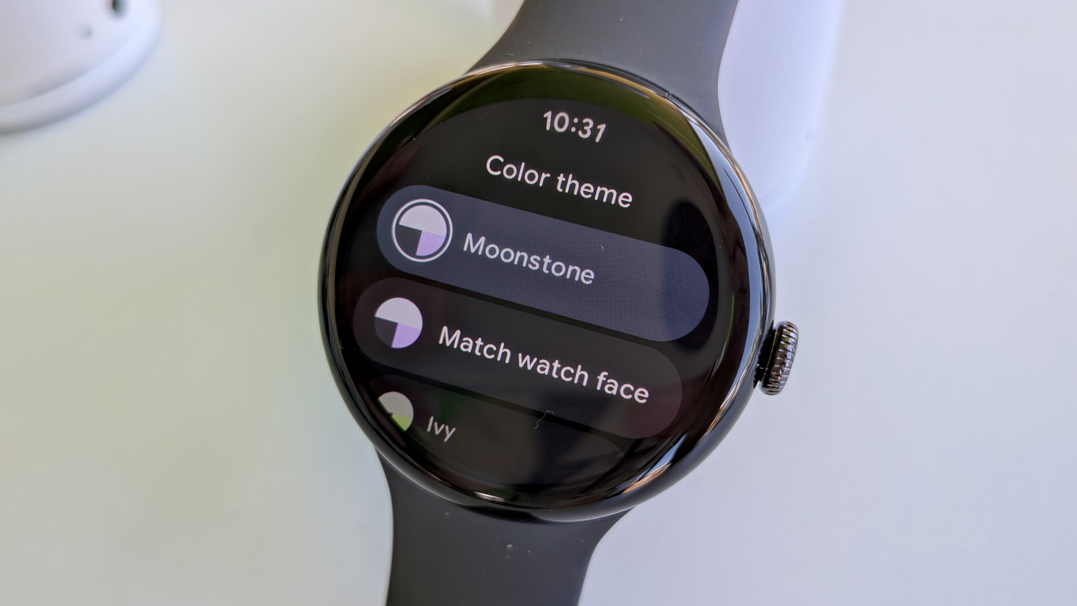 The Color theme settings screen on Wear OS 6 on the Pixel Watch 3, showing the primary "Match watch face" view and some set theme options like Moonstone and Ivy.