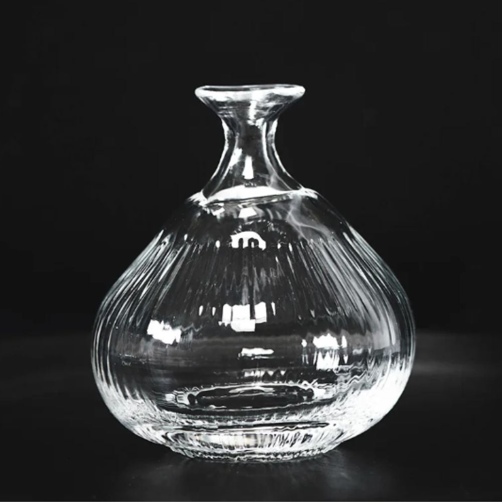 clear glass onion bud vase on black background