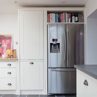 White kitchen units, black floor tiles, large fridge freezer