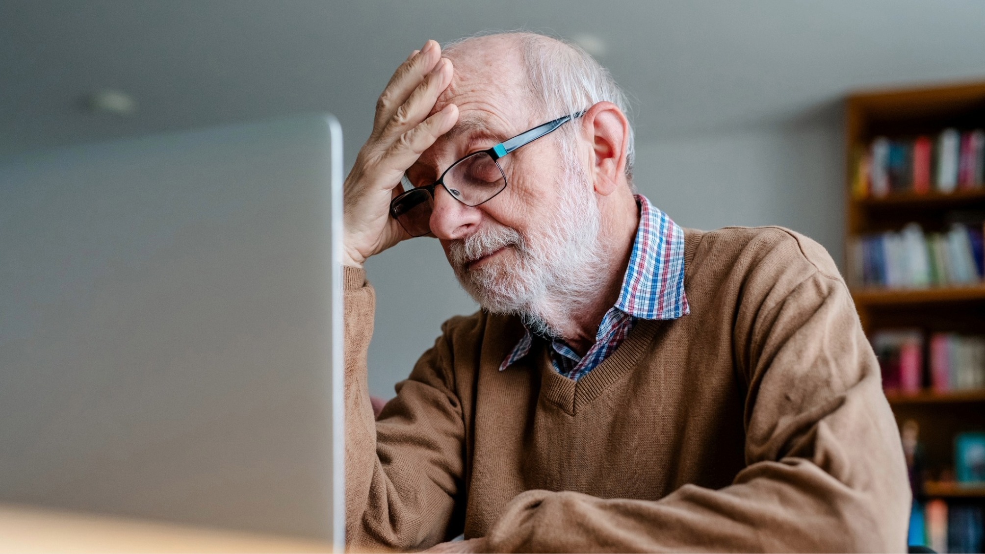 Old man working on laptop and looking worried