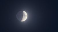 A half-lit moon is photographed in a starry night sky with its right side lit.