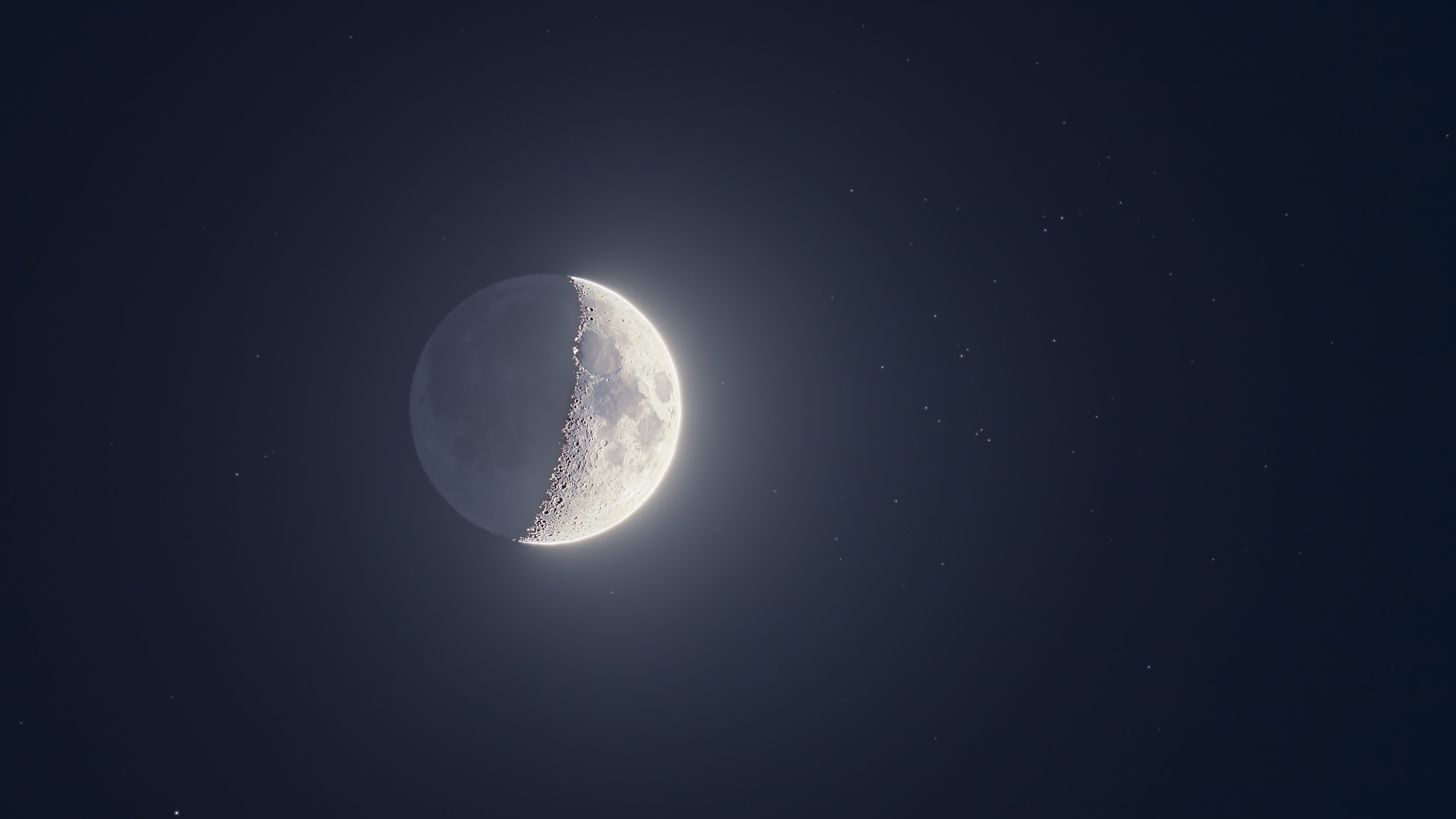A half-lit moon is photographed in a starry night sky with its right side lit.