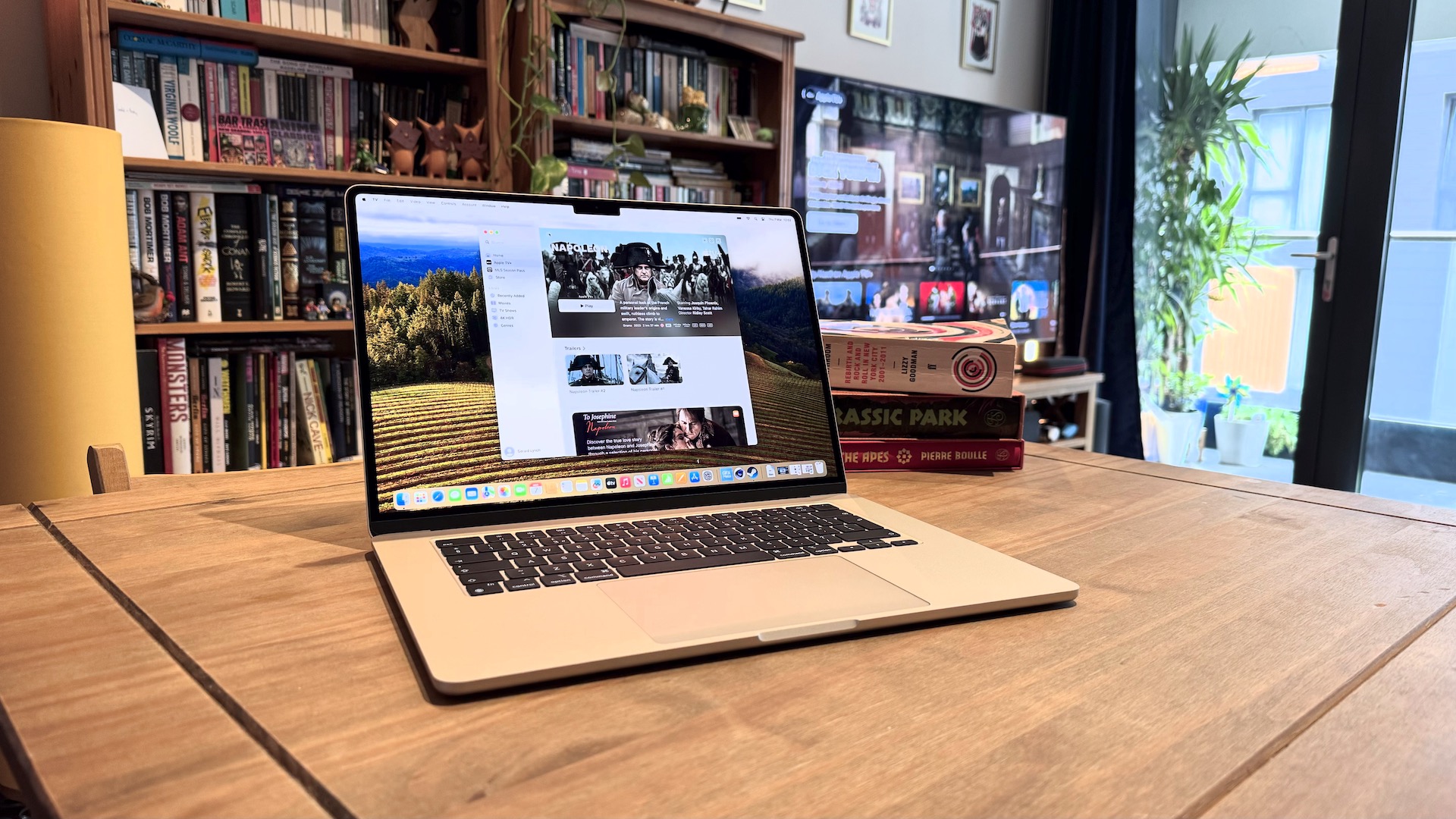 The 2024 MacBook Air M3 on a wooden table in front of a bookshelf.