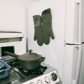 Sage green oven mitts hung up on kitchen fridge