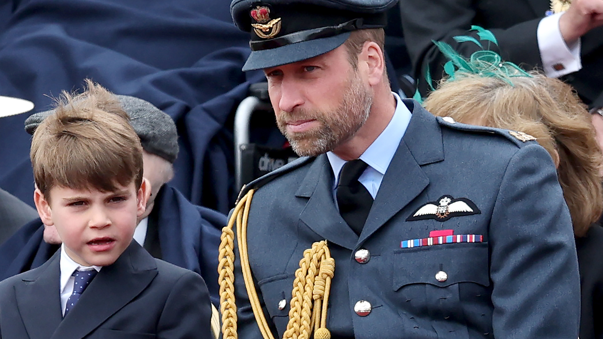 Prince Louis wearing a suit sitting next to Prince William, wearing a military uniform, at a VE Day parade