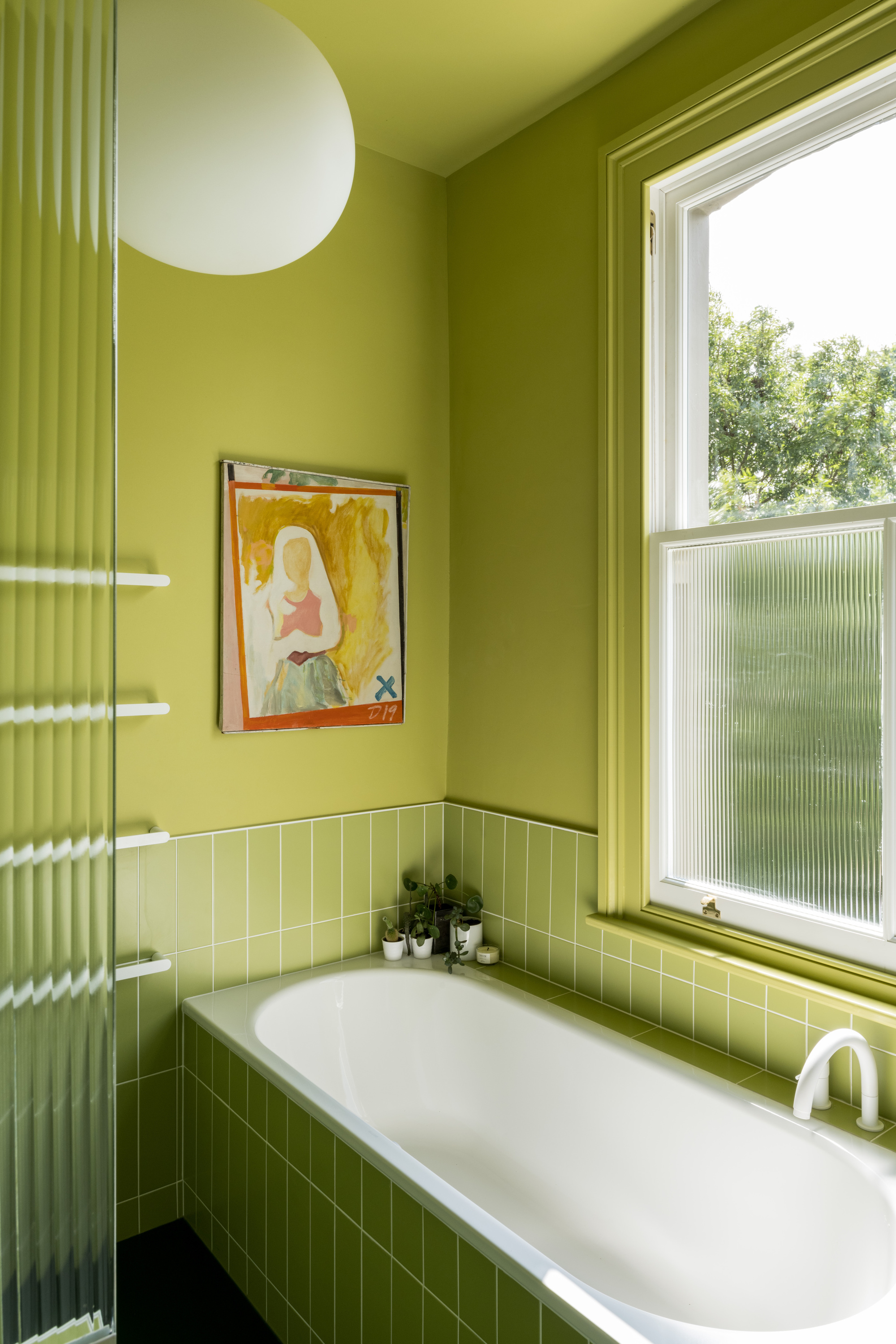 matcha green bathroom with paint and walls, artwork, fluted window, built-in bath and white tap