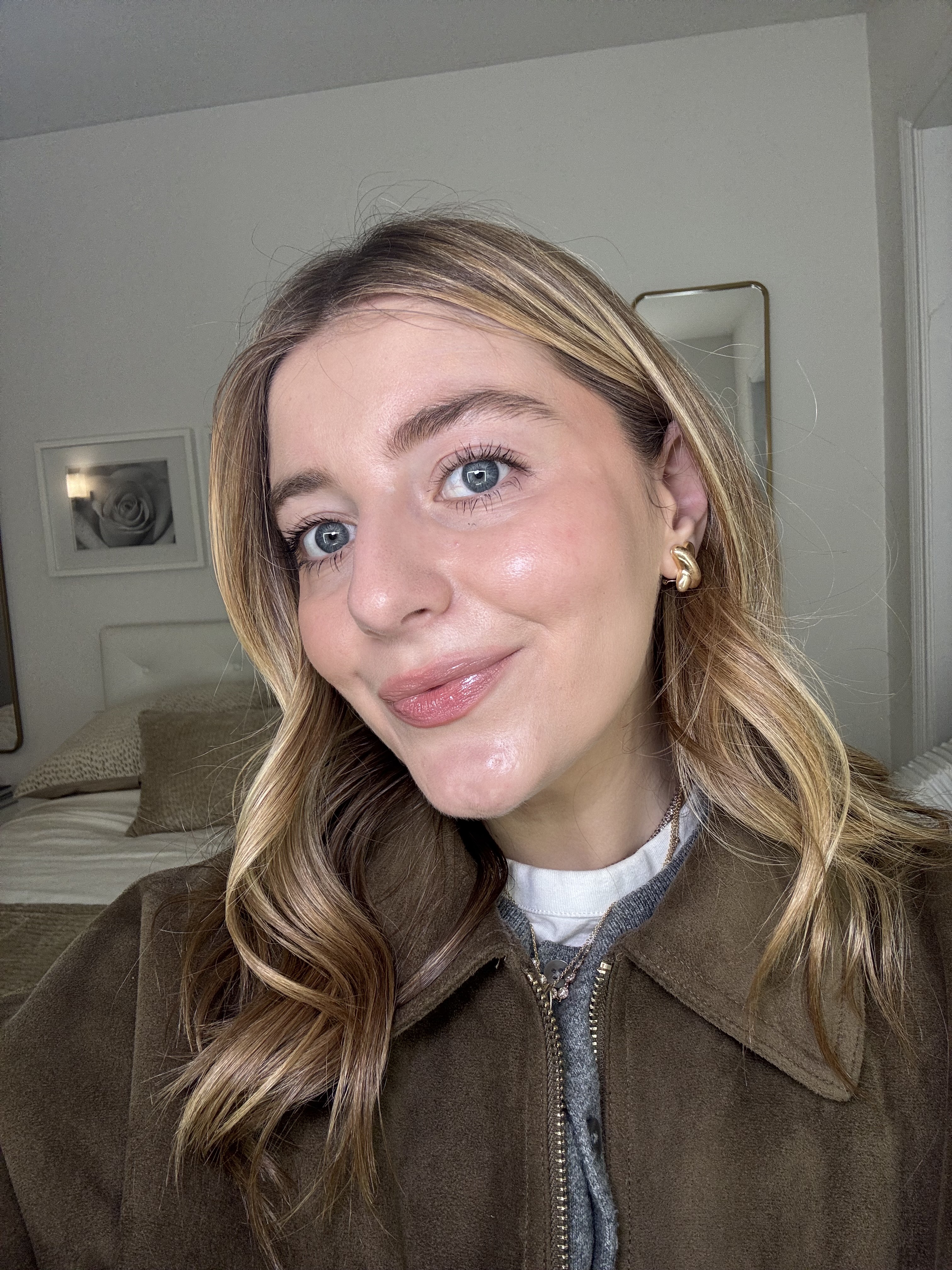 a woman with blonde hair in a brown jacket with glowing skin