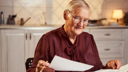Older woman checks paperwork at table