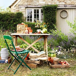 Alfresco garden potting table, green folding bistro chair, vintage drawers, seed trays, hessian sacks, flowerpots, exterior of stone cottage, string holder CH&I 10/2010 pub orig
